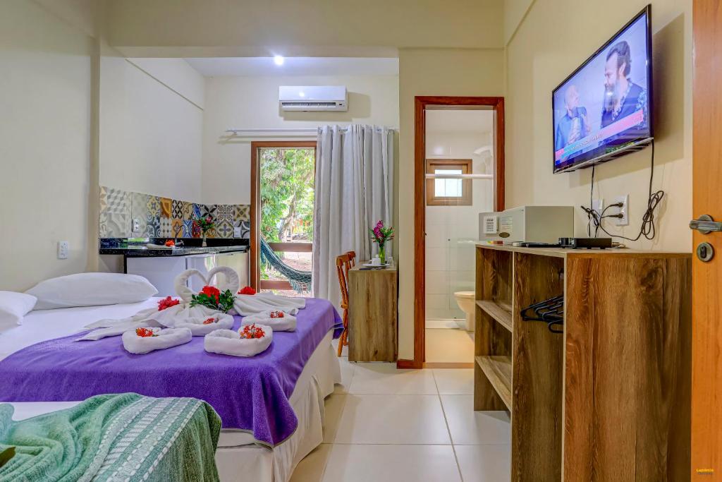 um quarto de hotel com uma cama roxa e uma casa de banho em i9 Quixaba Flat em Itacaré