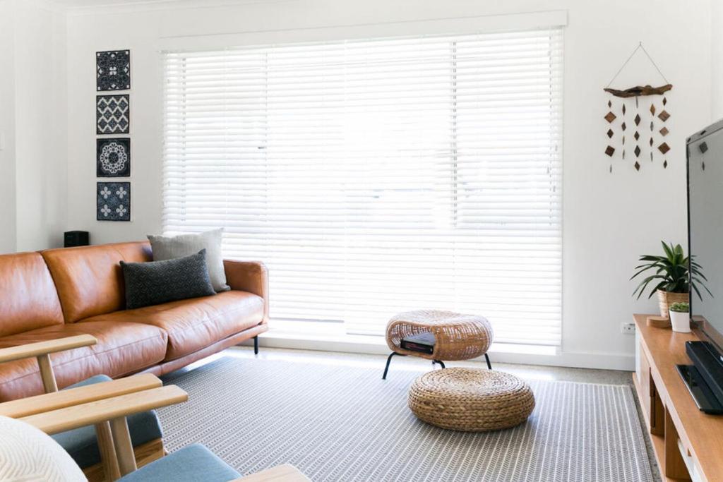 a living room with a leather couch and a stool at Casa Del Mar 10 - Seaside Family Home in Pottsville