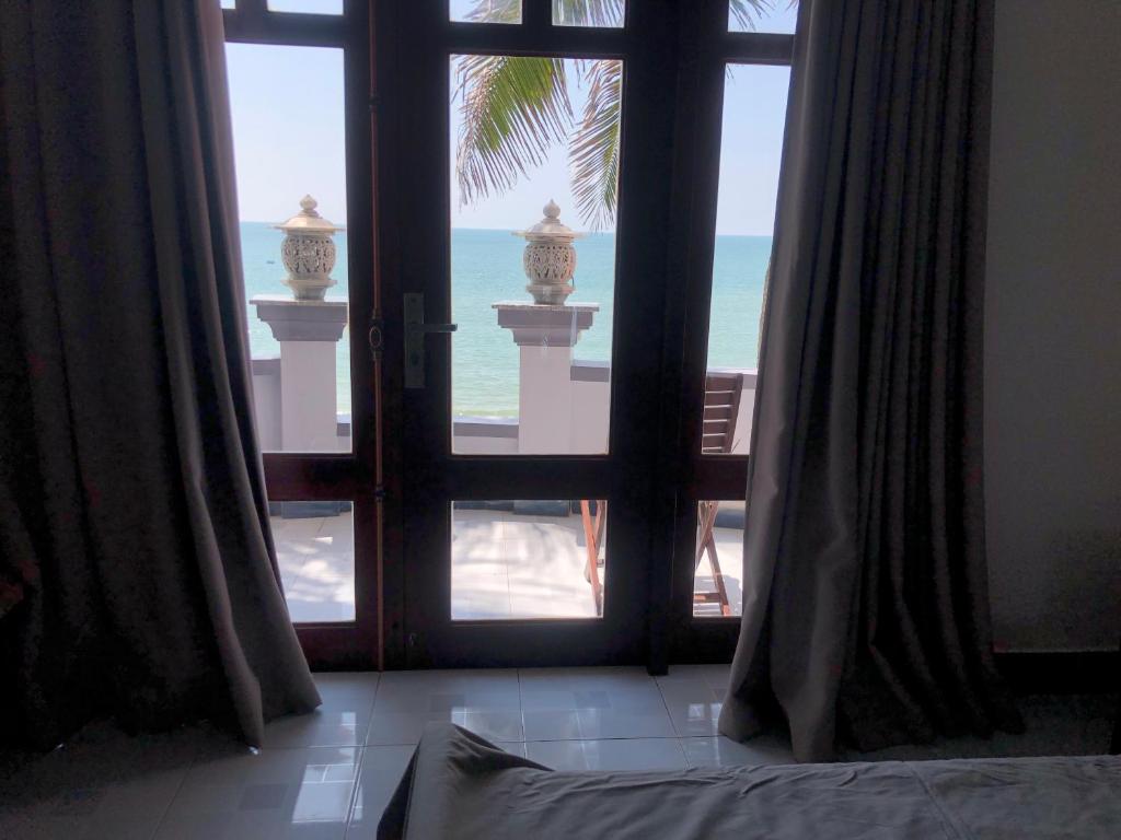 um quarto com uma janela aberta com vista para o oceano em Tulip Mui Ne em Phan Thiet