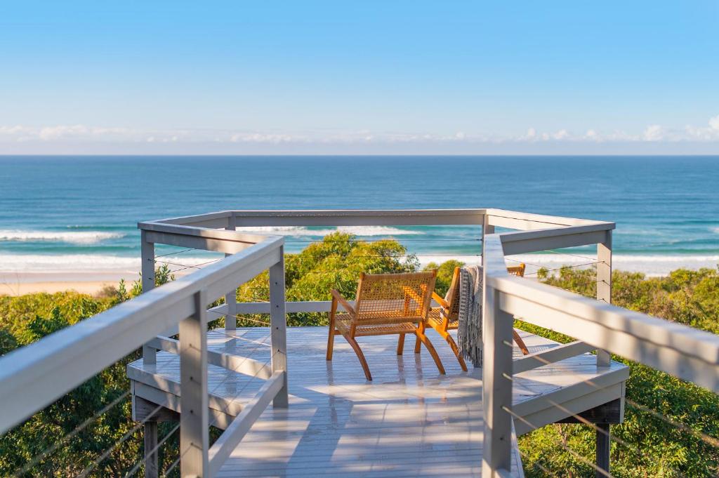 a deck with a table and chairs on the beach at Seascape @ 19 Pindari - privacy, space, views in Dunbogan