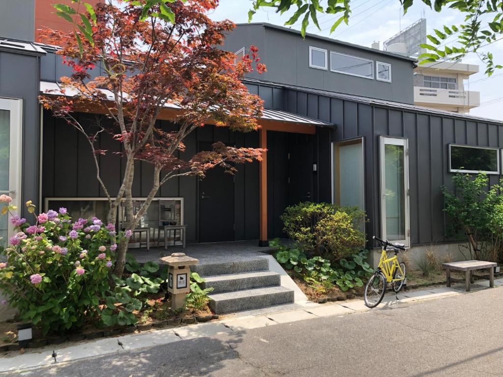 Kamome Jyuku في تاكاماتسو: منزل أسود مع دراجة متوقفة أمامه