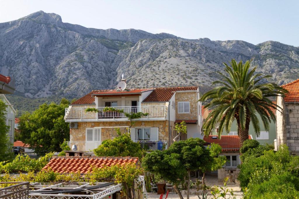 une maison avec un palmier et des montagnes en arrière-plan dans l'établissement Apartments Kaktus Orebic, à Orebić