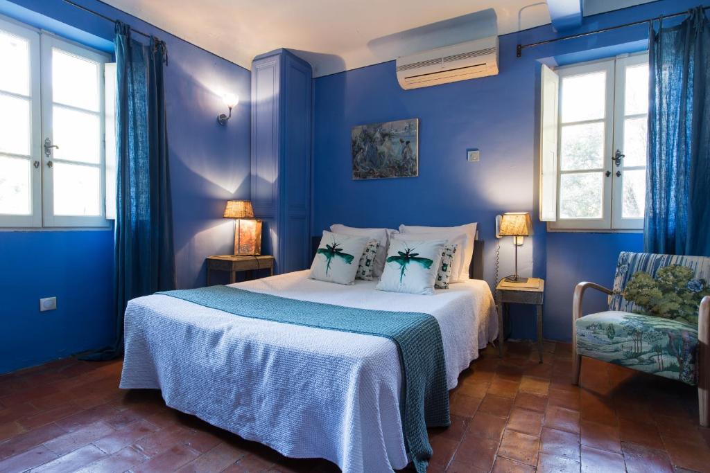 um quarto azul com uma cama e uma cadeira em Le Jardin d'Emile em Cassis