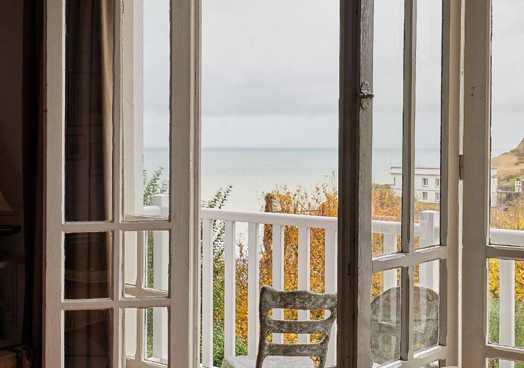 an open window with a chair looking out at the ocean at Villa Les Cormorans, Vue Mer, 10 personnes in Ault