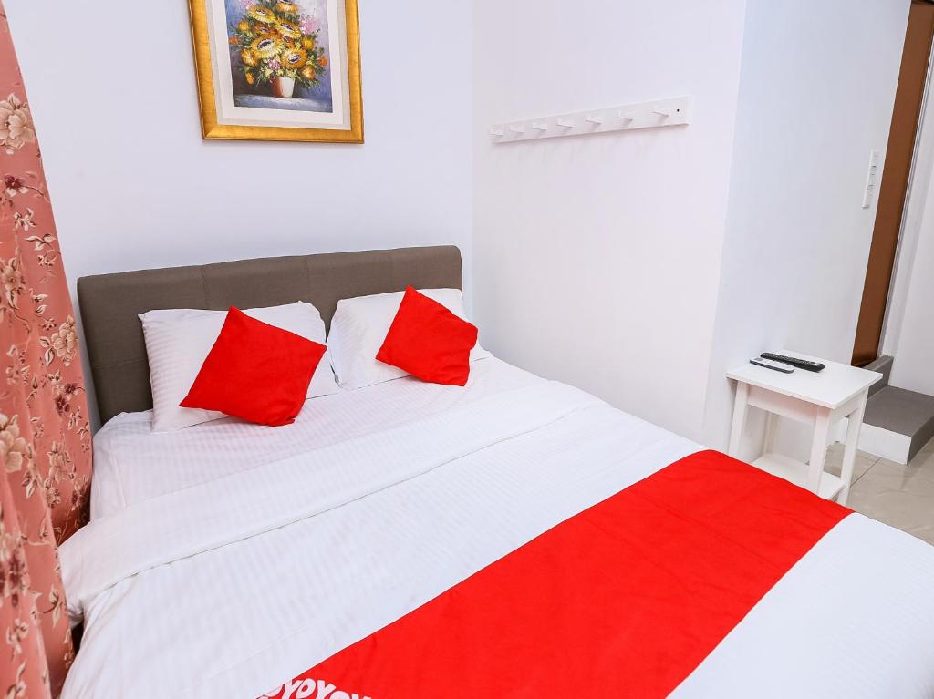 Schlafzimmer mit einem Bett mit roten und weißen Kissen in der Unterkunft OYO 89772 Roselyn Inn in Johor Bahru