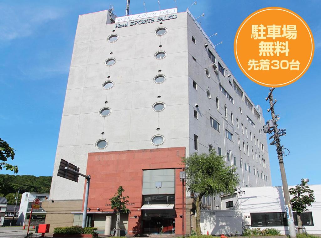 Un alto edificio bianco con un cartello davanti di Hotel Sports Palko a Gifu