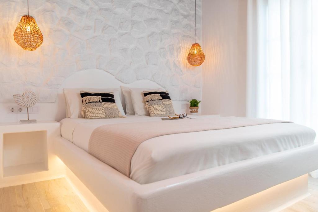 - une chambre blanche avec un grand lit blanc et des oreillers dans l'établissement En Lefko boutique house, à Naxos Chora