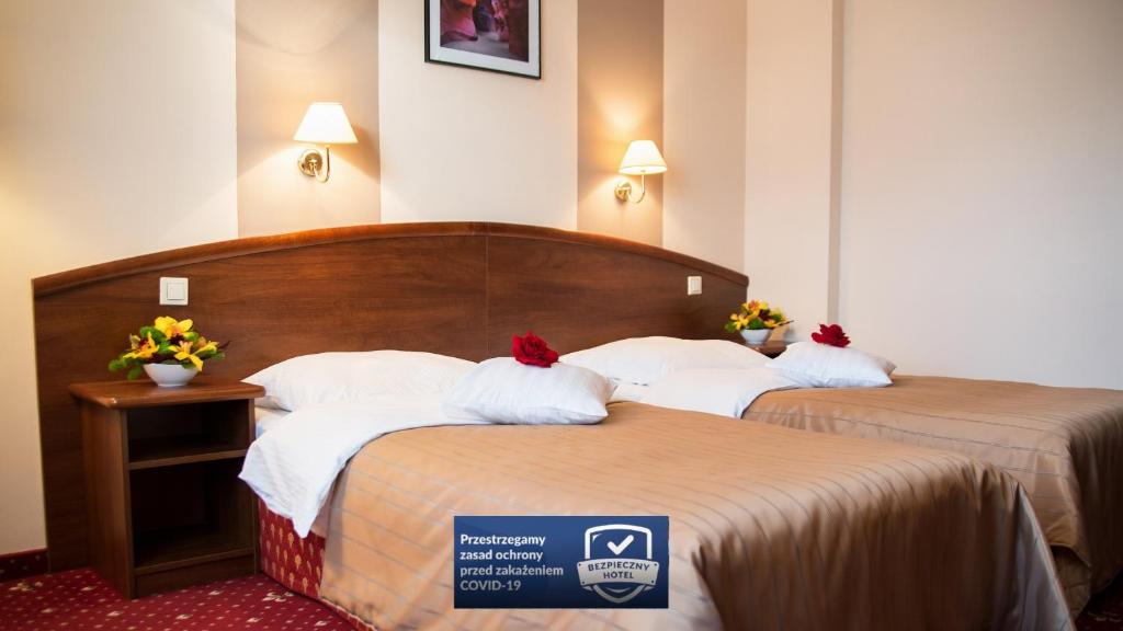 two beds in a hotel room with a sign on them at Hotel Novum & Spa in Niepołomice