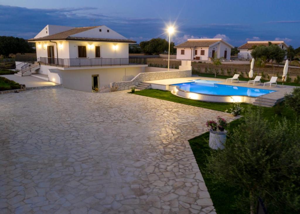une arrière-cour avec une piscine et une maison dans l'établissement Casa vacanze IL MANDORLO, à Scicli