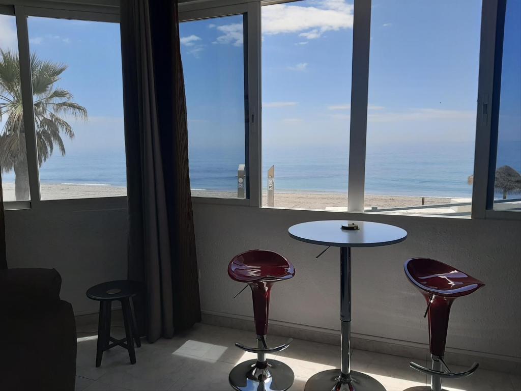 ネルハにあるPlaya Torecilla Beachfrontのビーチを望む客室で、テーブル1台とスツール2脚が備わります。