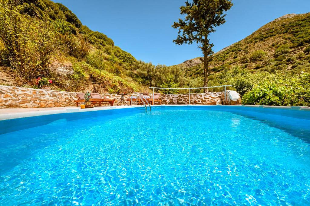a swimming pool with a mountain in the background at Ellafos Traditional Living in Loúkhiou