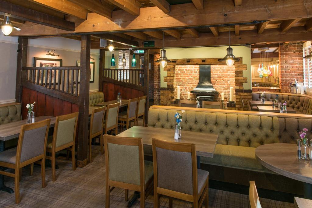 restauracja ze stołami i krzesłami oraz bar w obiekcie The Barns Hotel w mieście Cannock