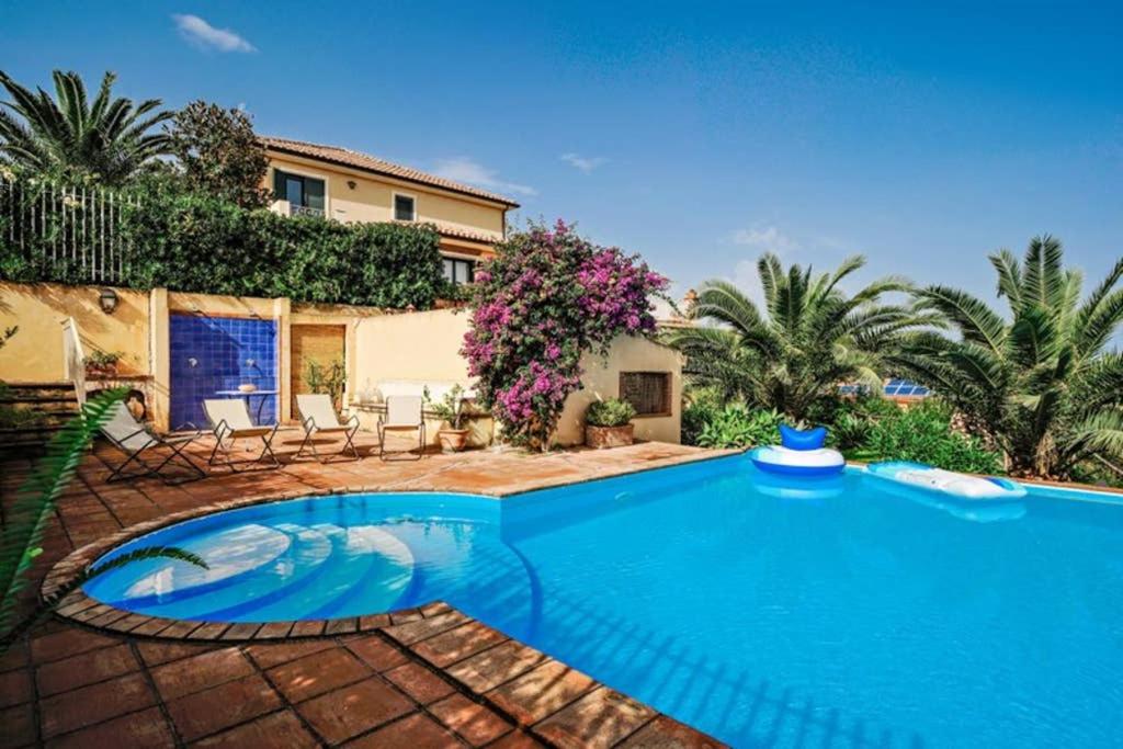 una gran piscina azul frente a una casa en Villa Fontanelle, en Patti