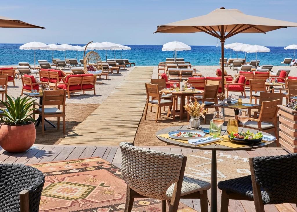 a restaurant on the beach with tables and chairs at Hôtel Barrière Le Gray d'Albion in Cannes