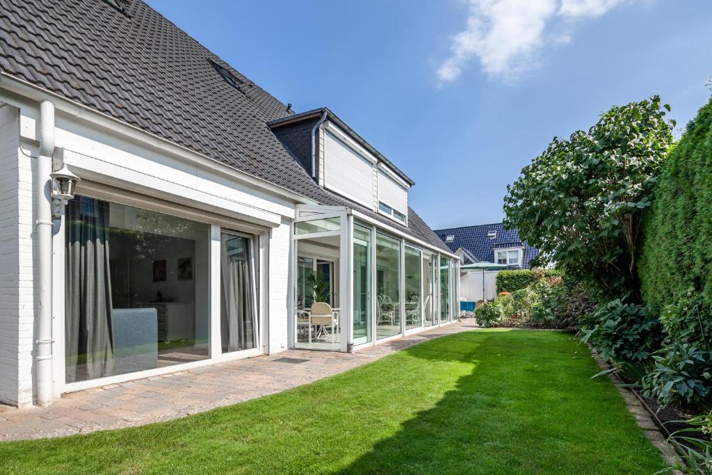 uma extensão de uma casa com portas de vidro e um quintal em Gästehaus Wendland - Timmendorfer Strand em Timmendorfer Strand