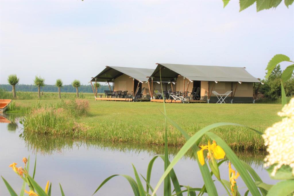a luxury tent with a lake in front of it at Safaritenten 'Woody' in Kuinre