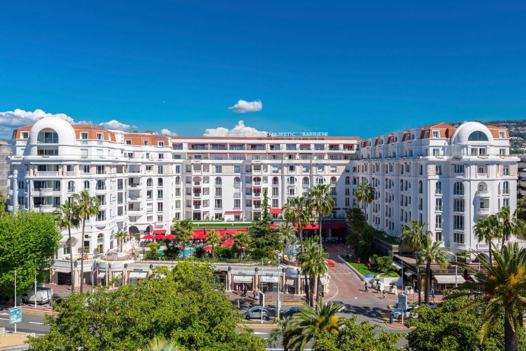 un gran edificio blanco con palmeras delante en Hôtel Barrière Le Majestic Cannes en Cannes