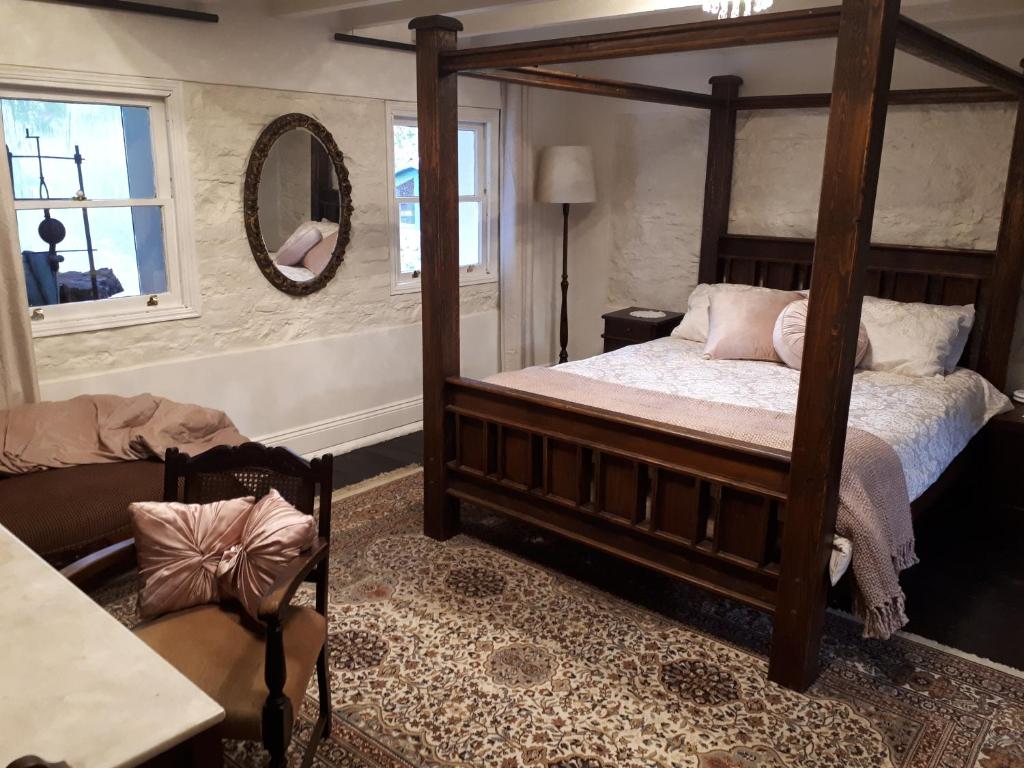 1 dormitorio con cama con dosel y espejo en Tanilba House en Lemon Tree Passage