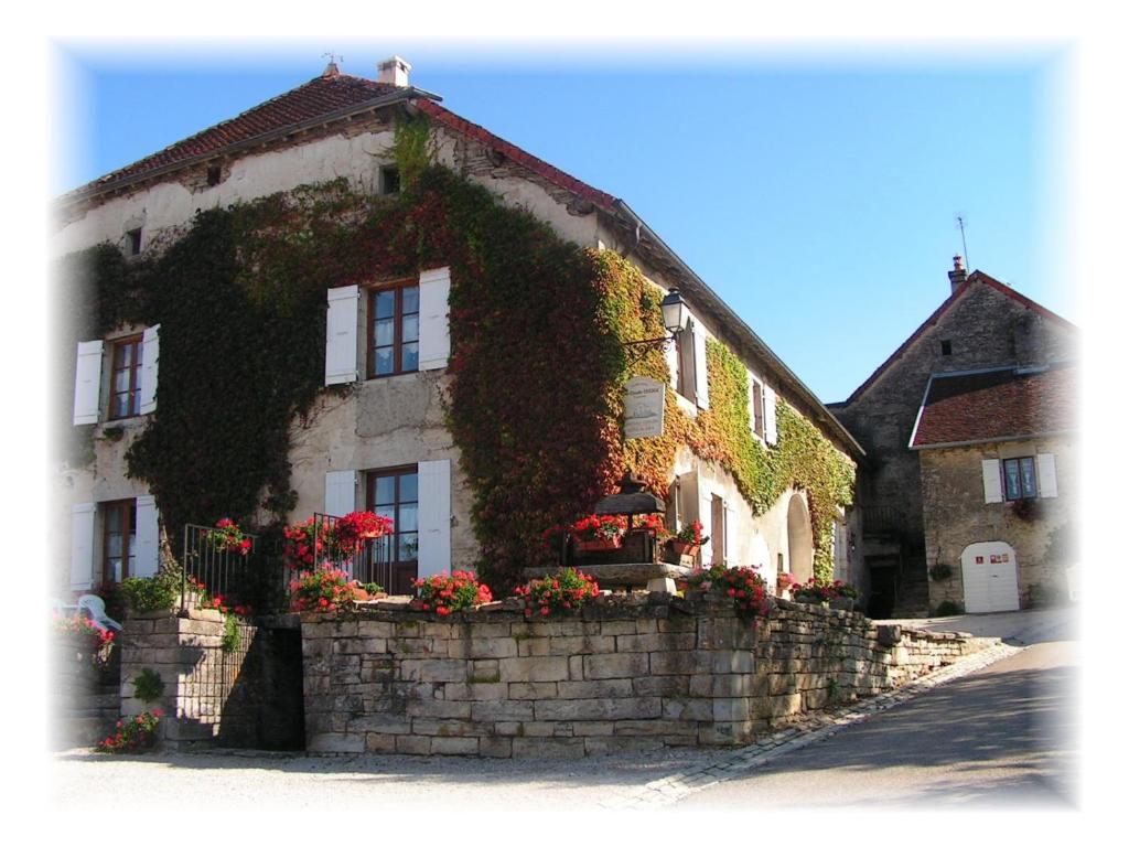 un bâtiment avec des fleurs sur son côté dans l'établissement Le CLOS DE L AMANDIER, à Château-Chalon