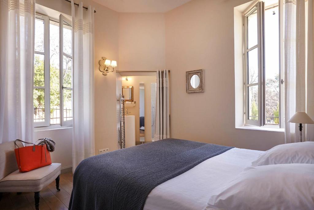 a bedroom with a large bed with a red bag on it at Château Les Carrasses in Capestang