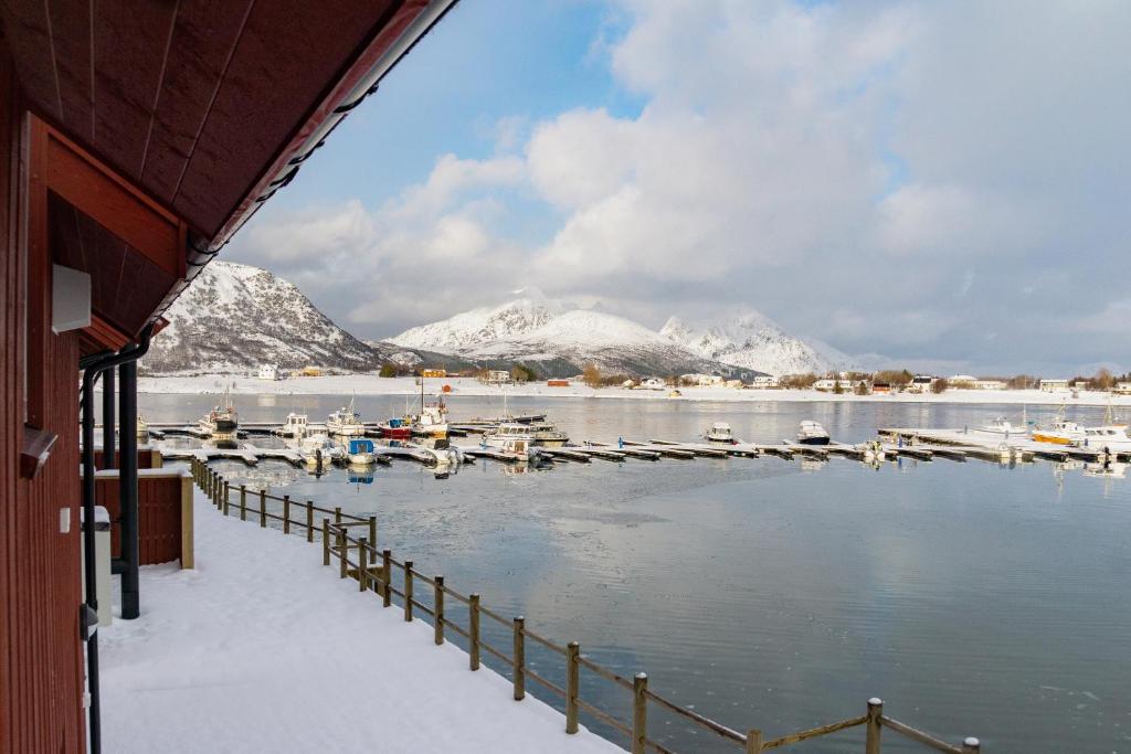 a marina with boats in the water with snow covered mountains at Brand new Nappstraumen seaview cabin in Gravdal