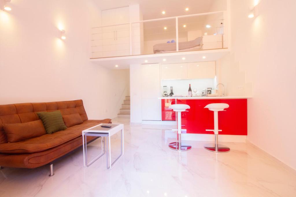 un soggiorno con divano e una cucina rossa di MEDANO4YOU The Loft 007 a El Médano