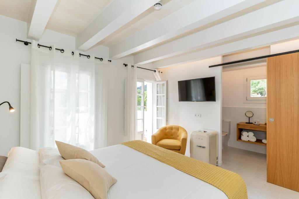 a white bedroom with a white bed and a television at Hotel m - 27 in Es Mercadal