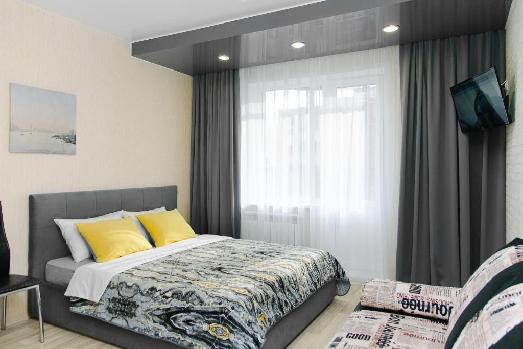 ノヴォシビルスクにあるCentral Apartment near by Marriott hotelのベッドルーム1室(黄色い枕のベッド1台、窓付)