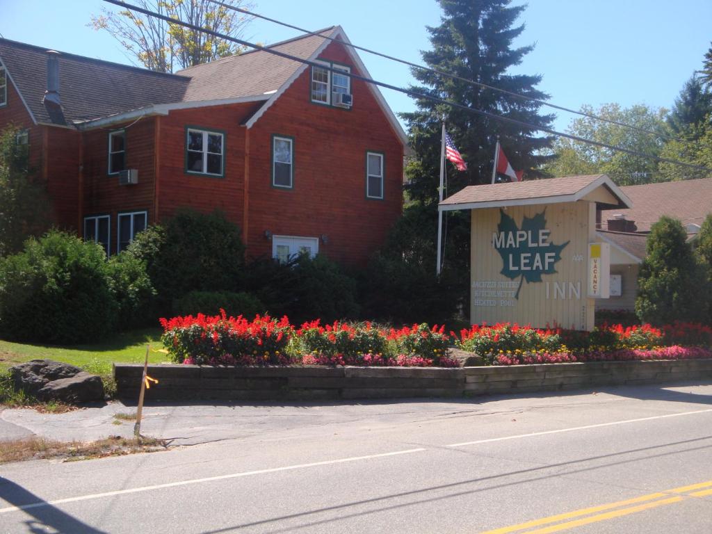 a red brick house with flowers in front of a street at Maple Leaf Inn Lake Placid in Lake Placid