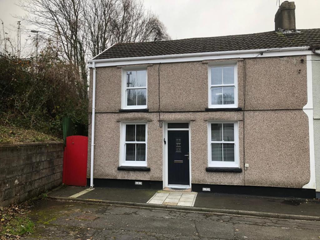 a house with a red door and white windows at Rj s house in Merthyr Tydfil