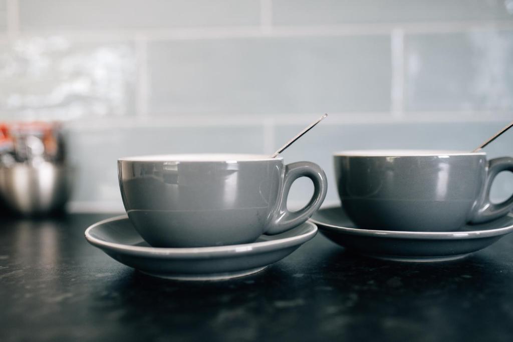 two coffee cups sitting on a table with spoons at The Fullerton Arms in Ballintoy