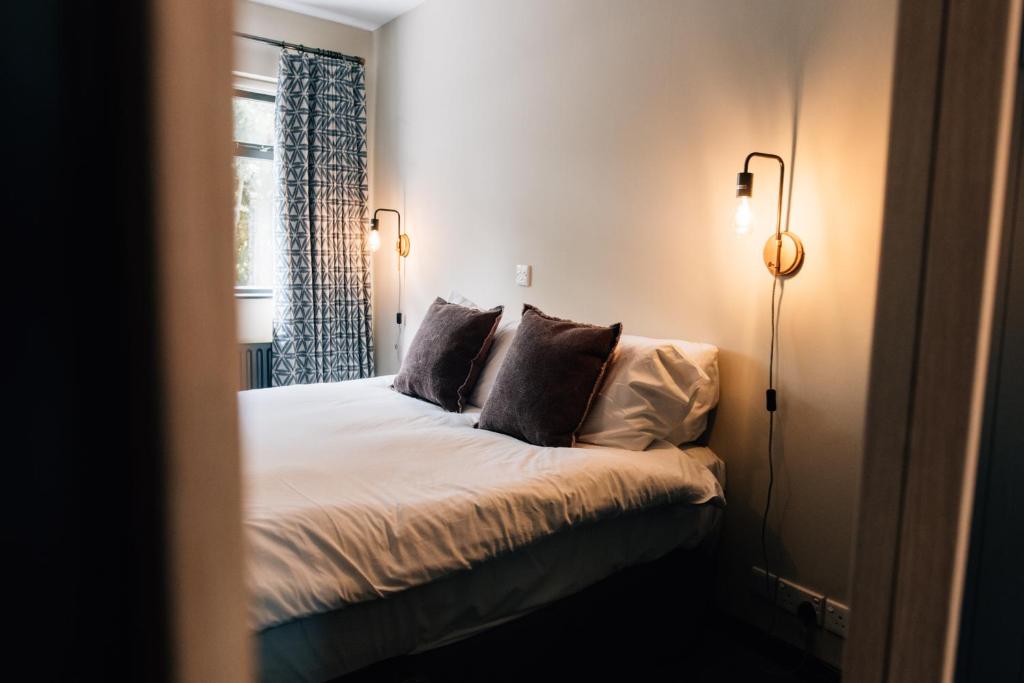 a bedroom with a bed with pillows and a window at The Fullerton Arms in Ballintoy