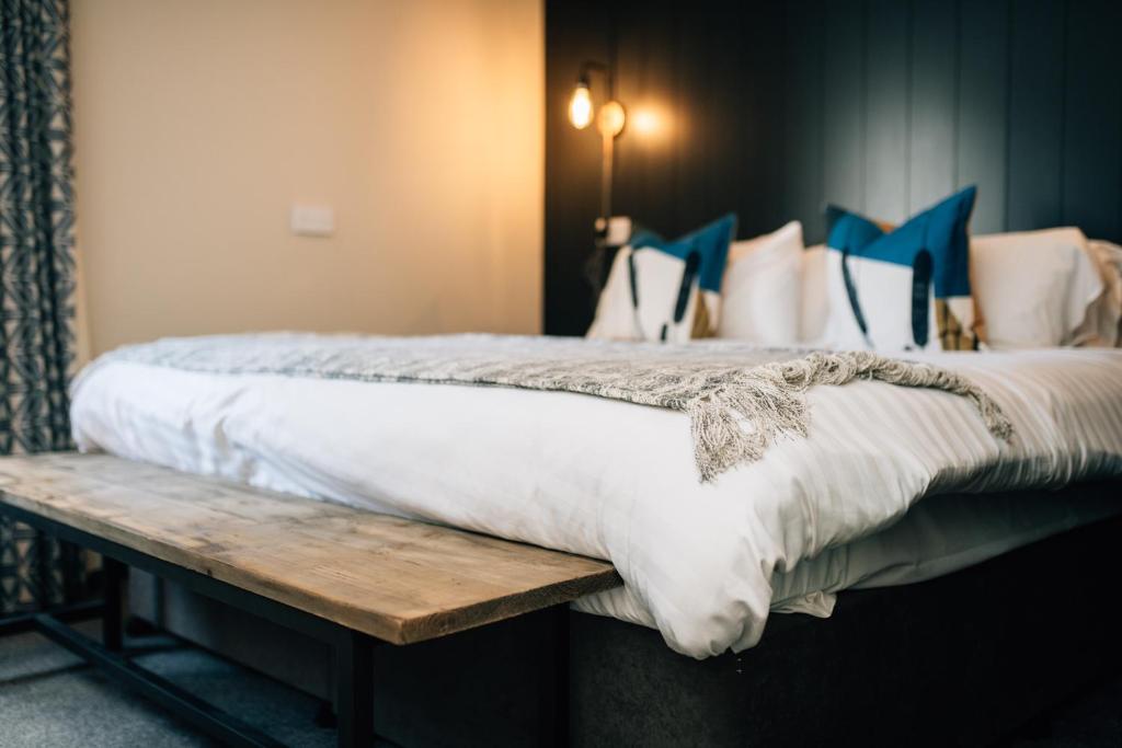 a bed with white sheets and pillows on a wooden bench at The Fullerton Arms in Ballintoy