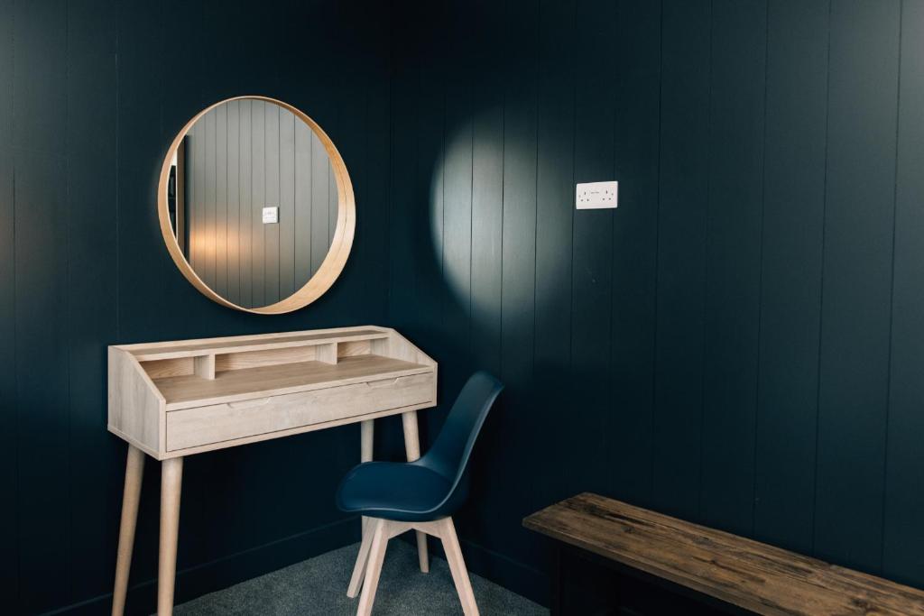 a vanity with a mirror and a blue chair at The Fullerton Arms in Ballintoy