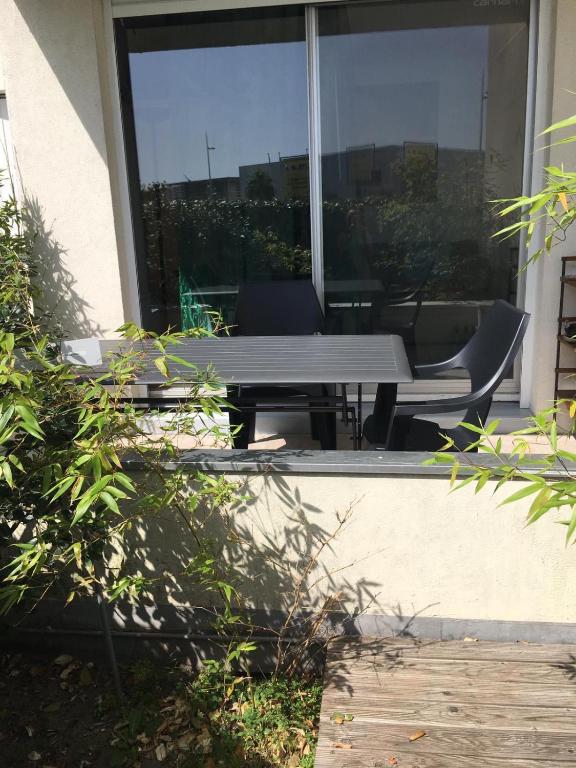 a patio with a table and chairs in front of a window at Appartement sympa Arcachon in Arcachon