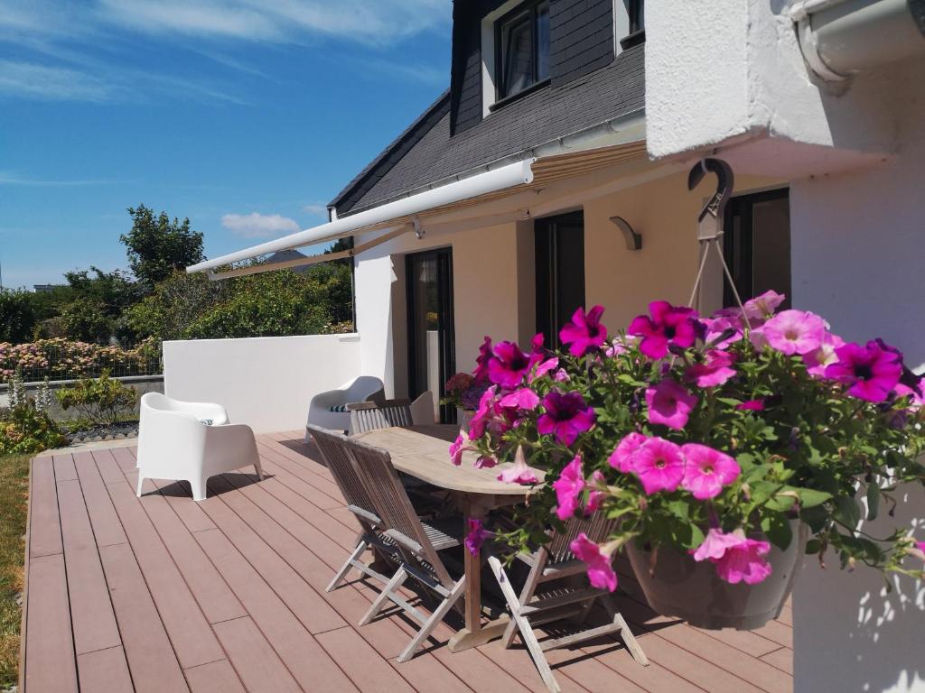 une terrasse avec des fleurs roses, une table et des chaises dans l'établissement Maison AN NEIZIG, à l'Île-Tudy