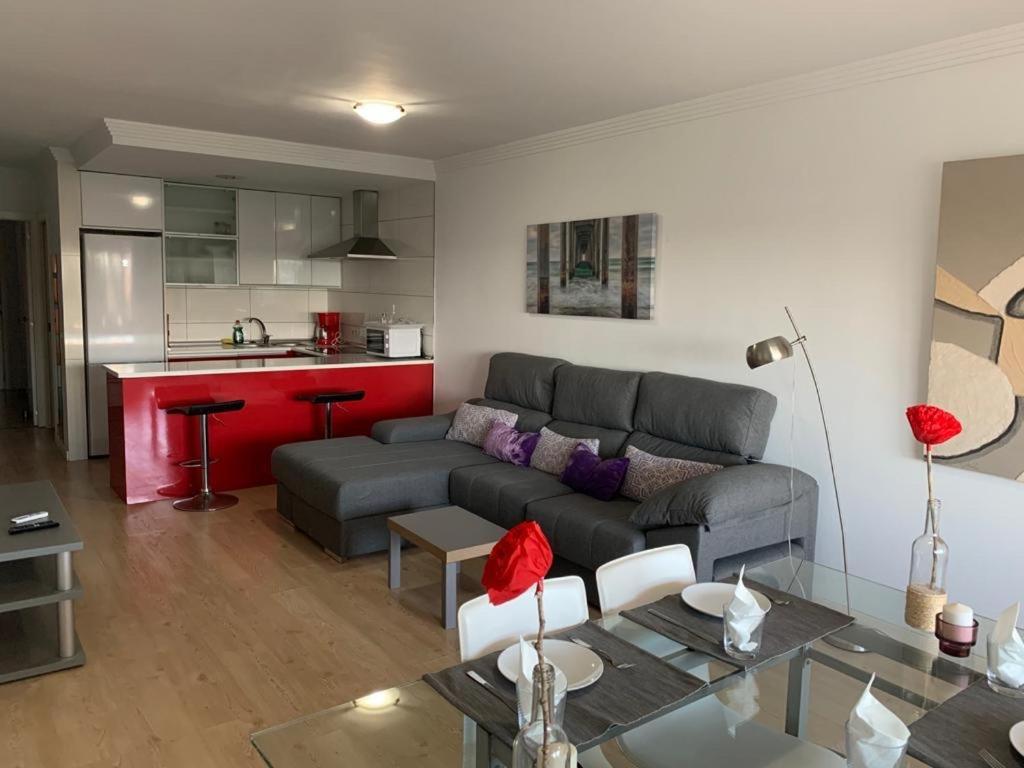 a living room with a gray couch and a kitchen at Apartment Puerto ALCUDIA in Port d'Alcudia