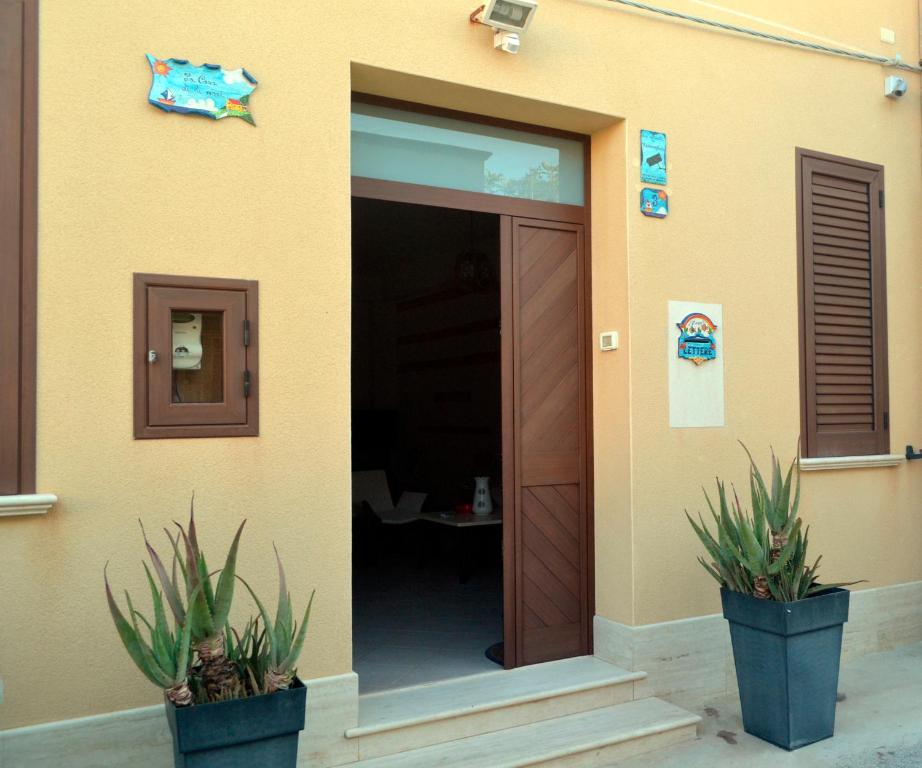 a building with two potted plants in front of a door at Casa di lu mari in Tre Fontane