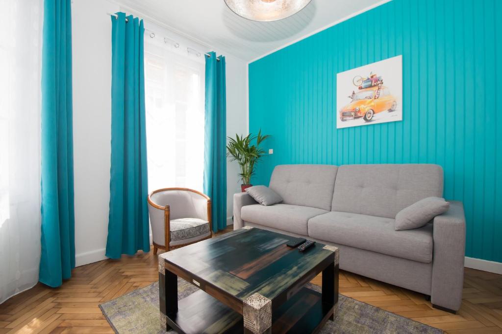 ein Wohnzimmer mit blauen Wänden, einem Sofa und einem Tisch in der Unterkunft L'épopée des coteaux 3☆ - centre ville - Epernay in Épernay