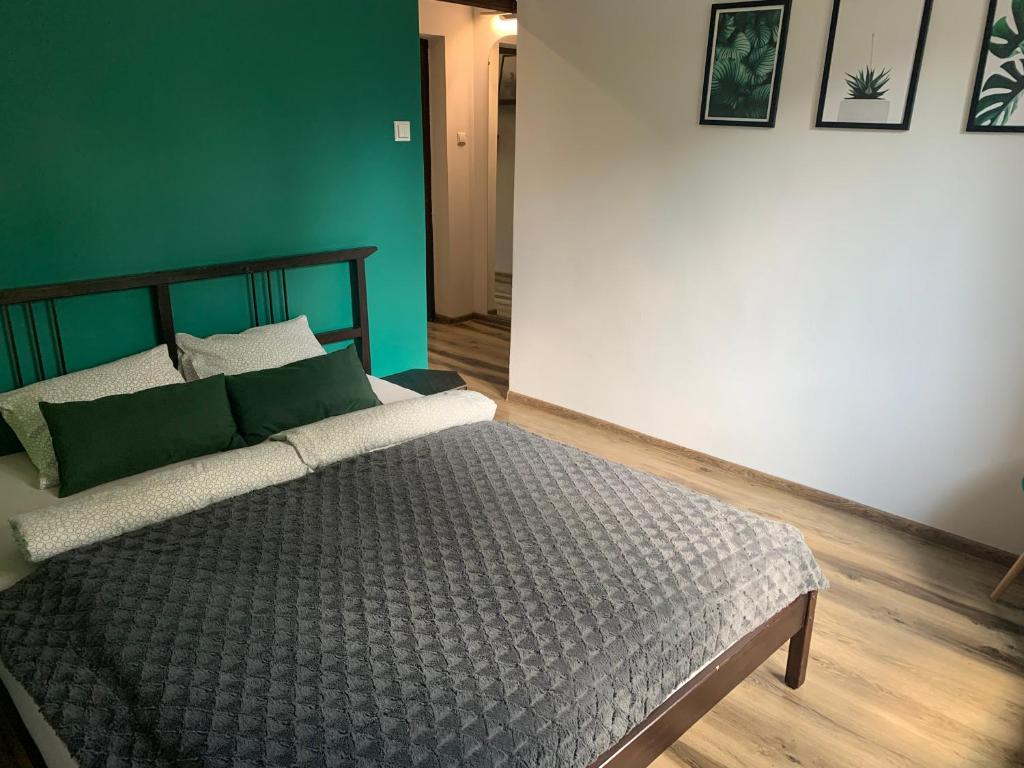a bed in a room with a green wall at Apartament z widokiem Tarnowskie Góry in Tarnowskie Góry