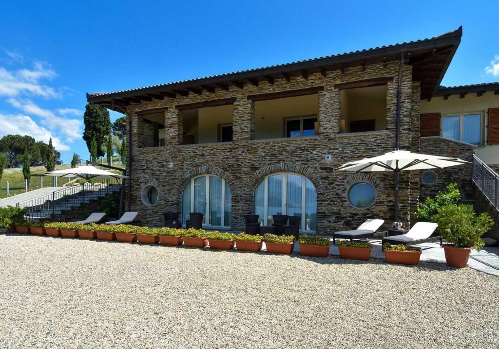 a house with chairs and an umbrella in front of it at Agriturismo Il Colle in Bellagio