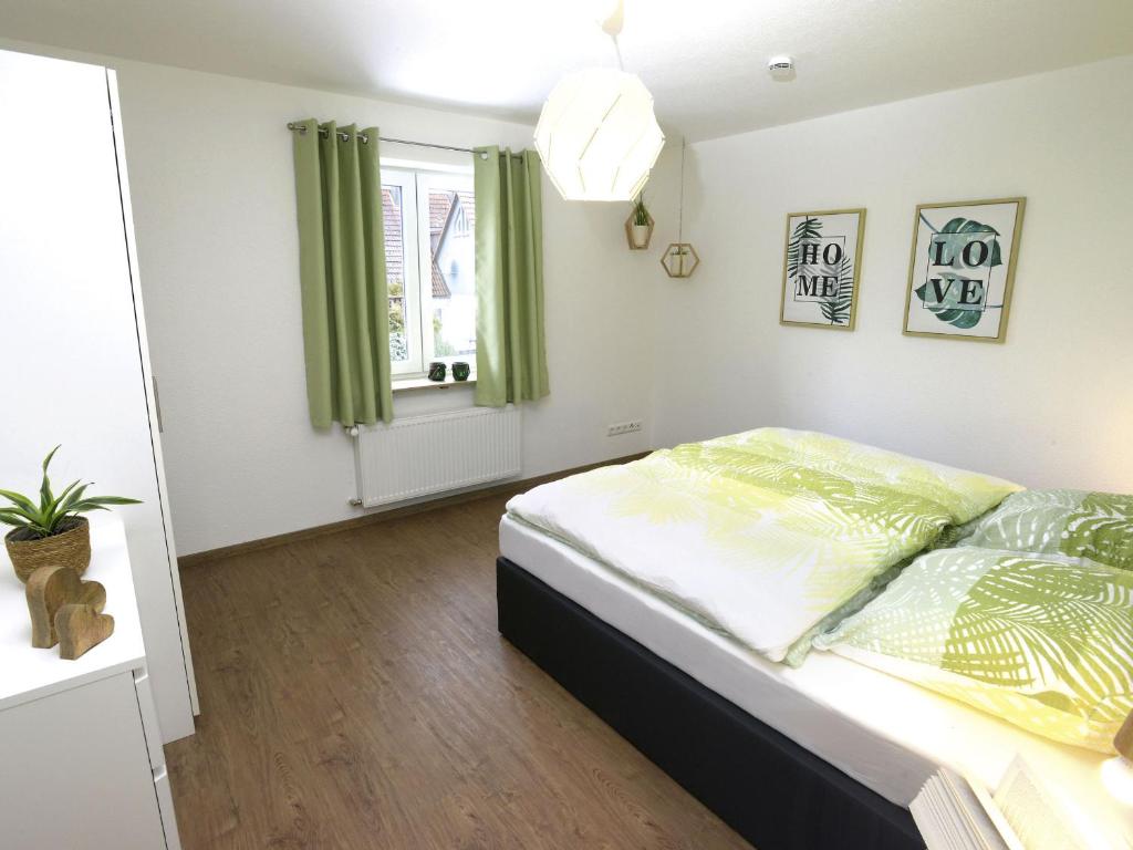 Schlafzimmer mit einem Bett mit grünen Vorhängen und einem Fenster in der Unterkunft Ferienwohnungen Schwarzwaldhäusle in Freudenstadt