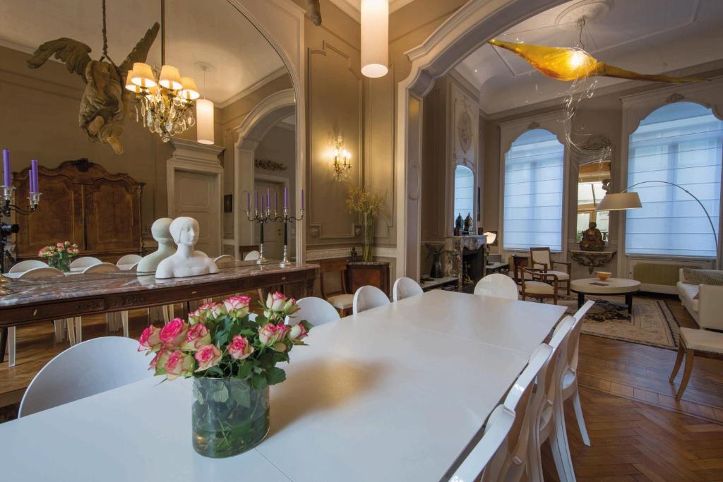 a dining room with a white table with flowers on it at Louise sur Cour in Brussels