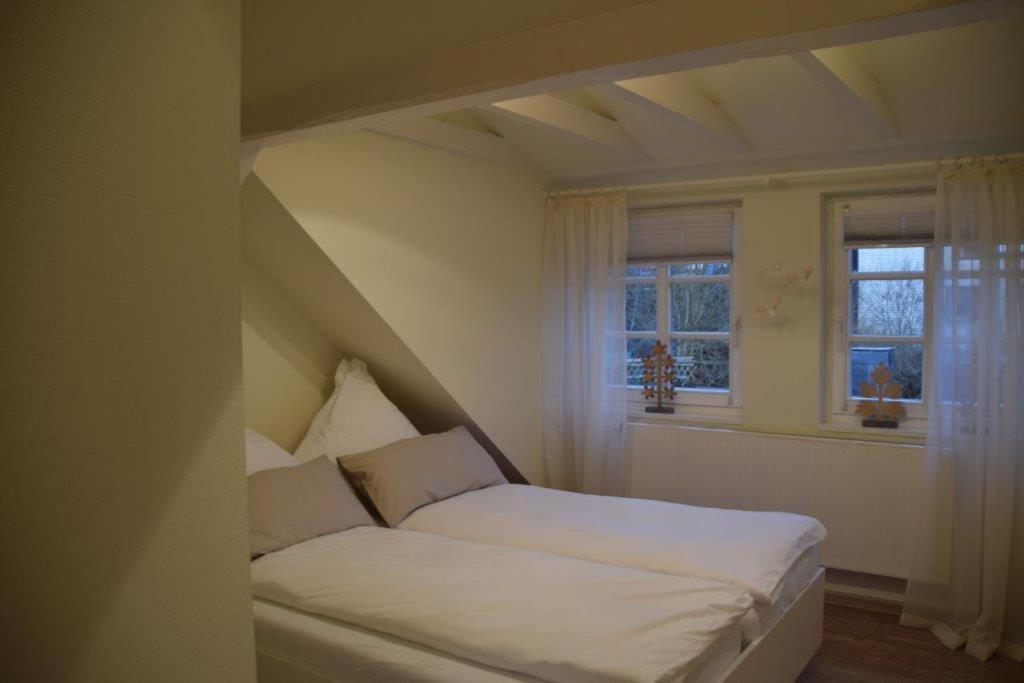Landgasthof Hüttenschenke في Kirchen: سرير أبيض في غرفة بها نافذتين