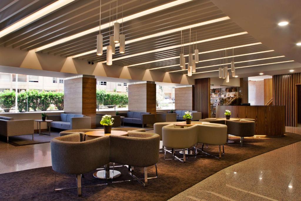 a lobby with tables and chairs in a building at Ramada by Wyndham Lisbon in Lisbon