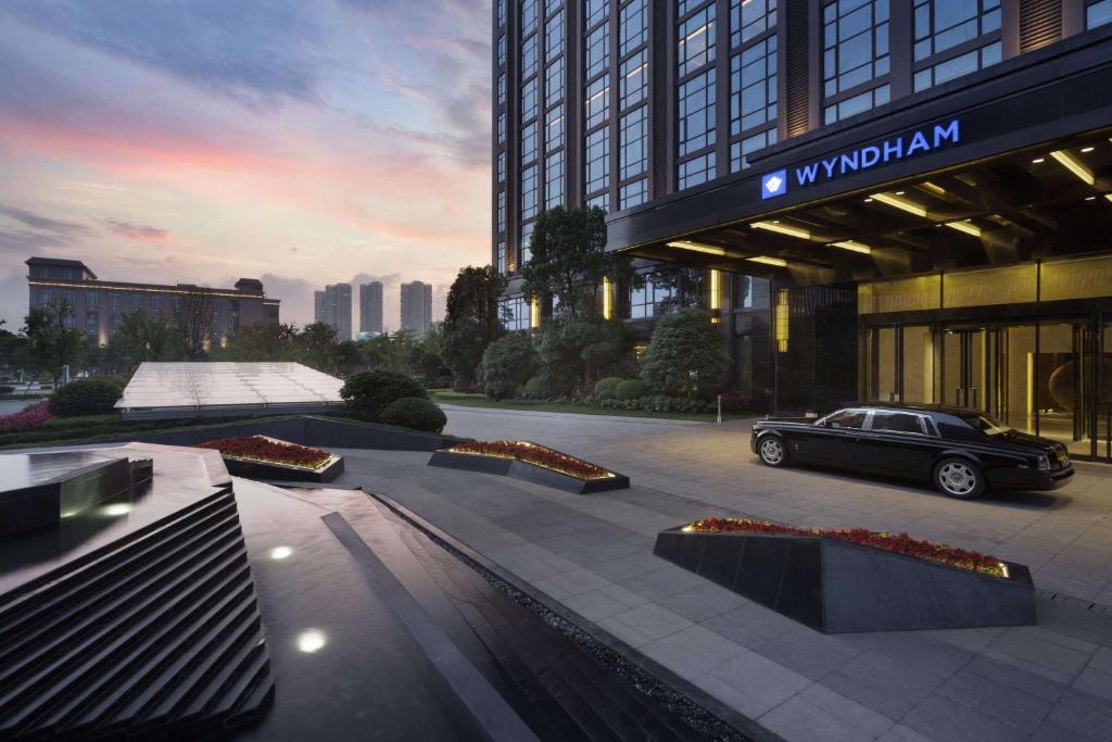 samochód stoi przed budynkiem w obiekcie Wyndham JinJiang Hotel w mieście Jinjiang