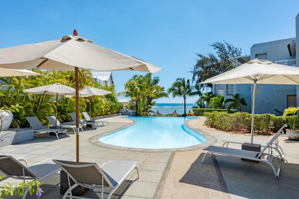 una piscina del complejo con sillas y sombrillas en Voile Bleue Boutique Hotel en Trou aux Biches