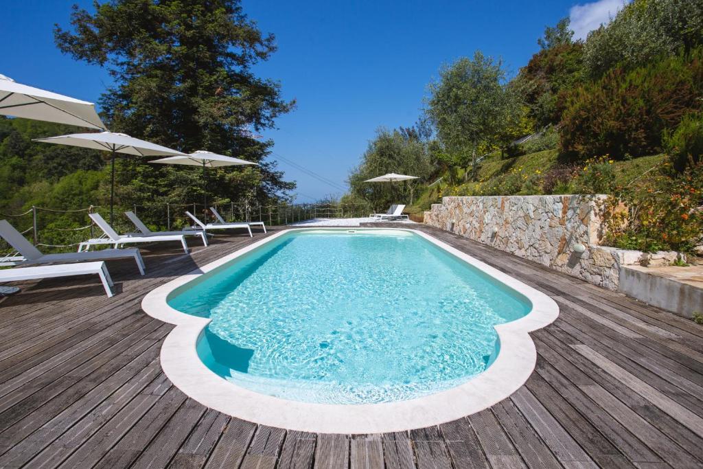 basen z leżakami i parasolami na drewnianym tarasie w obiekcie Villa Borgovecchio B&B w mieście Camaiore
