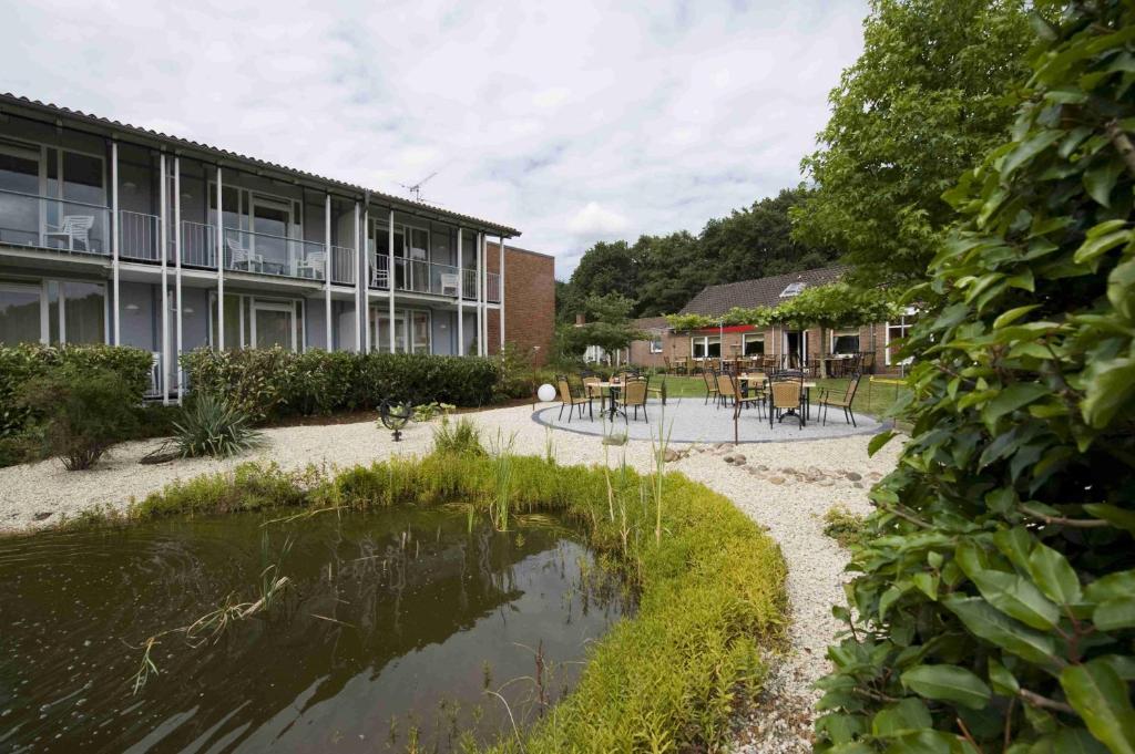 ein Gebäude mit einem Teich vor einem Gebäude in der Unterkunft Hotel am Waldbad in Uelsen