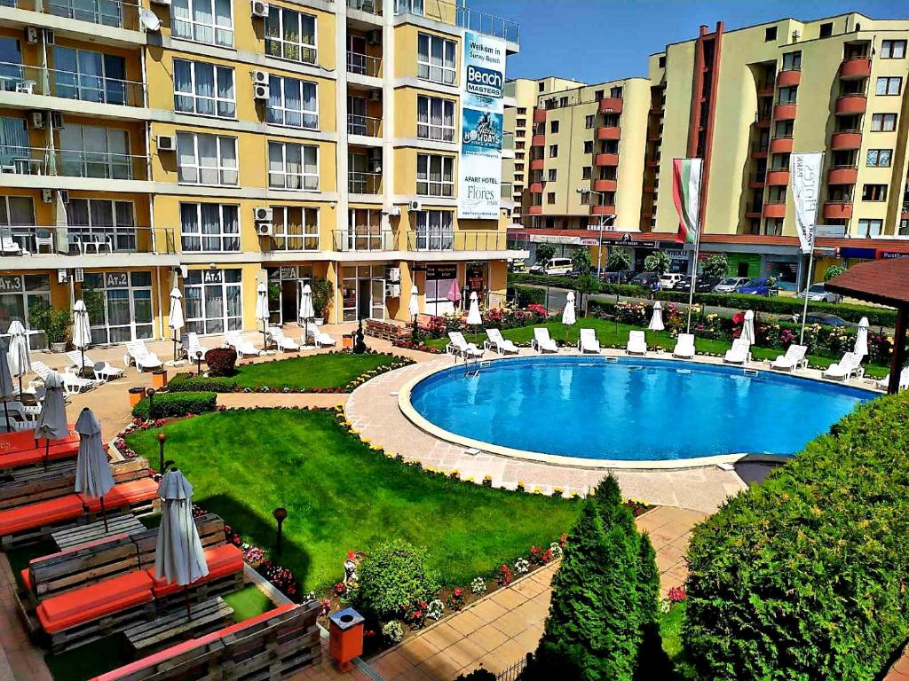 a large swimming pool in a resort with chairs and buildings at Flores Park in Sunny Beach